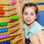 Cute little girl playing with abacus in kindergarten